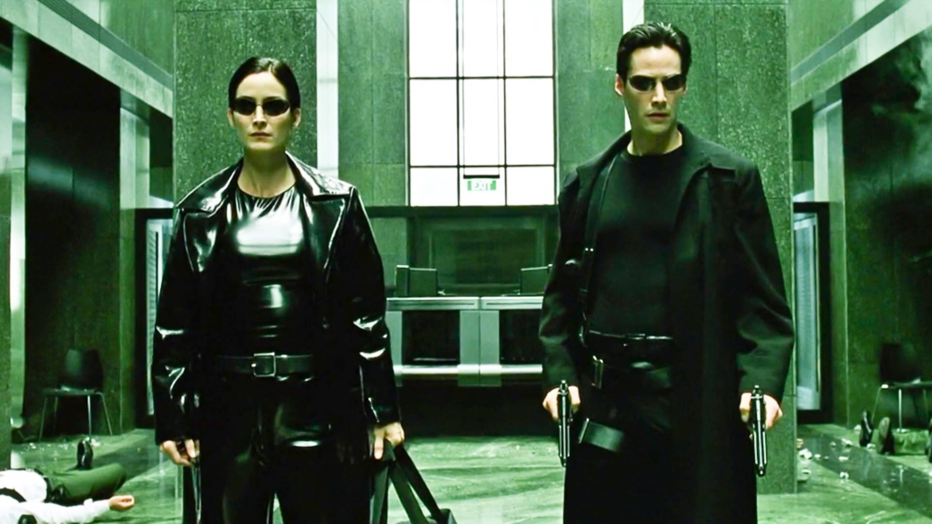 Neo 与 Trinity 站在绿色调的 Matrix 城市街道